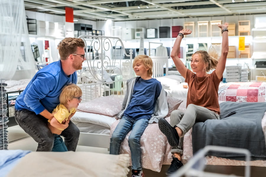 Familie probiert gemeinsam ein Sofa in einem IKEA Einrichtungshaus aus.